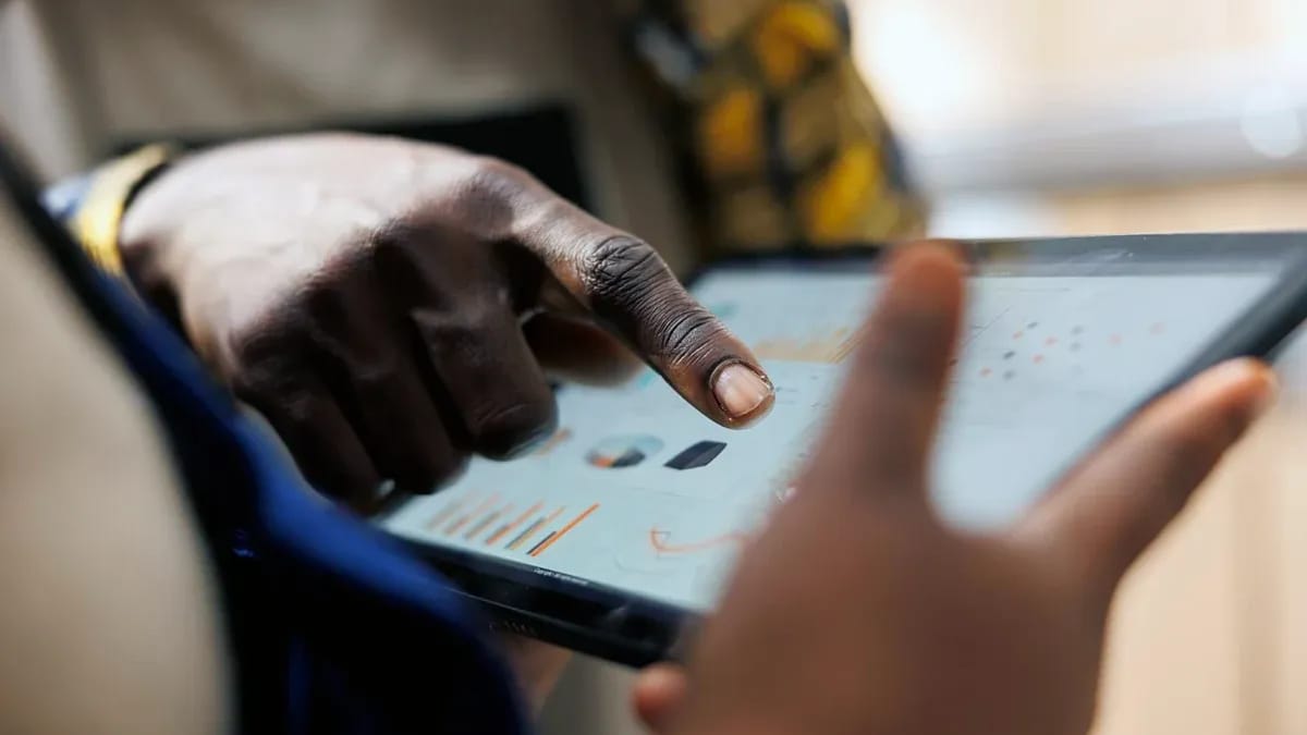 Close-up of a person pointing at charts on a tablet screen held by a colleague